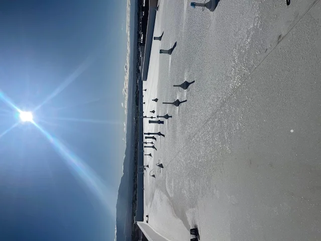 Individuals walk on a sunlit frozen lake, enjoying the crisp winter air and the beauty of the shimmering ice.